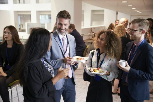 Colleagues holding plates of finger food at a corporate networking event