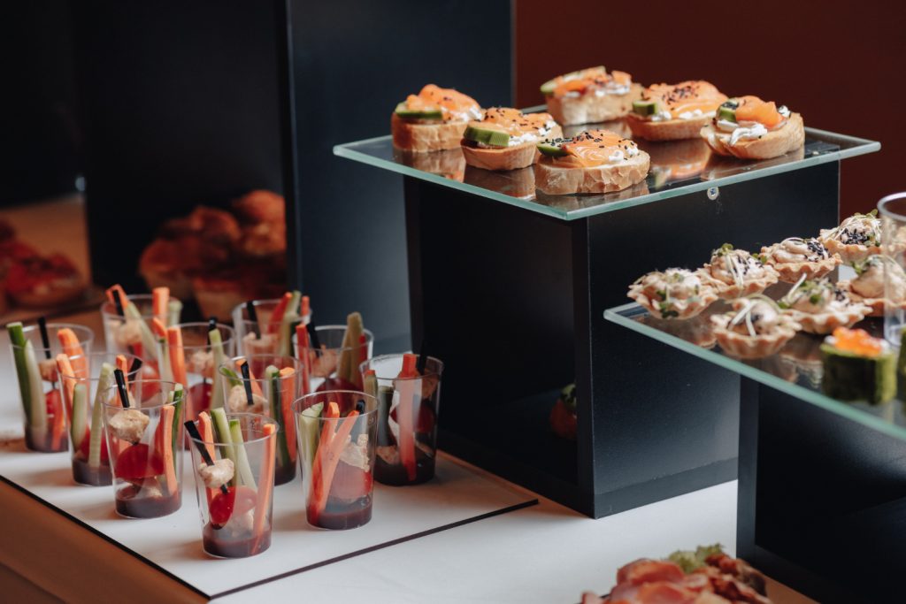 Smoked salmon canapés and vegetable cups on a glass catering stand